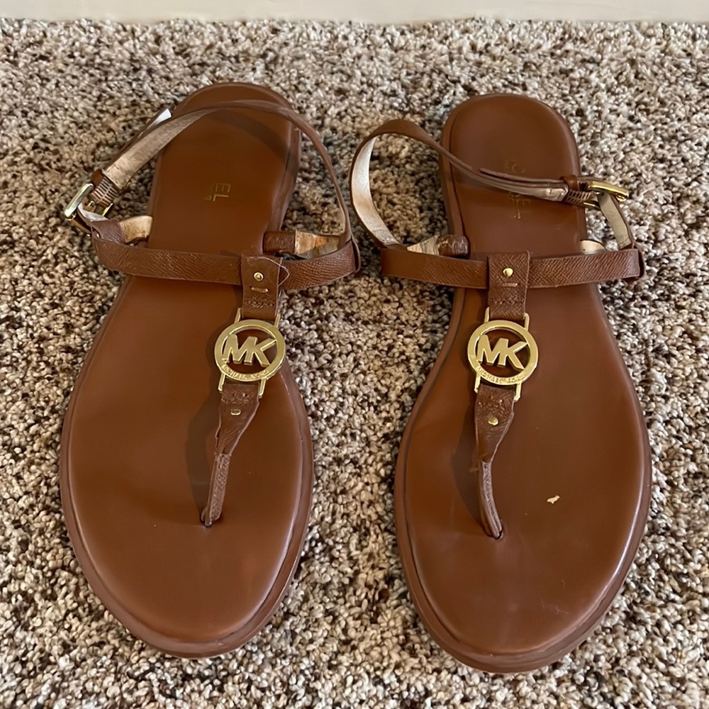 Michael Kors brown leather sandals with gold MK emblem.